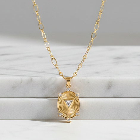 Gold necklace with a pendant on a marble surface