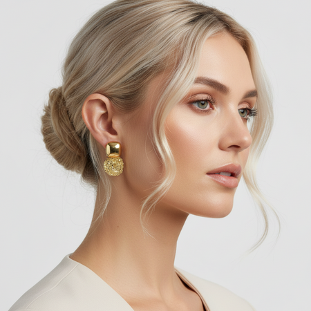Woman wearing gold earrings with a neutral background