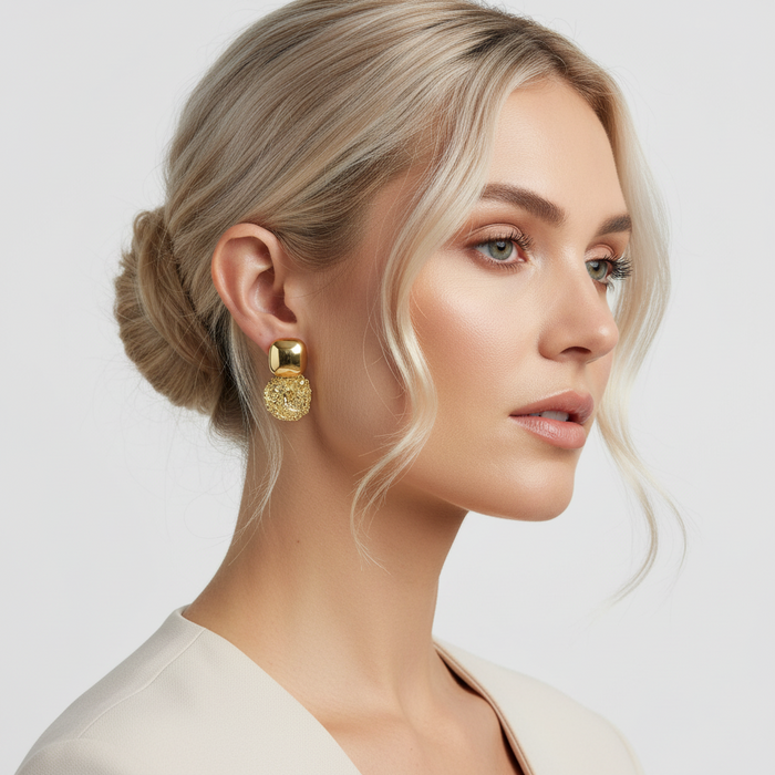 Woman wearing gold earrings with a neutral background
