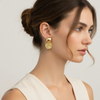 Woman wearing gold earrings with a neutral background