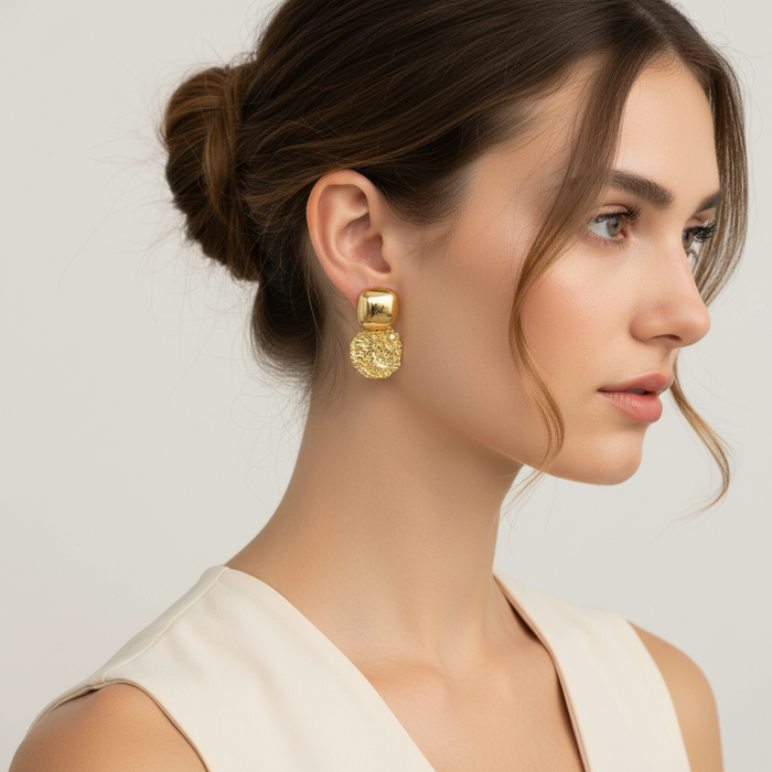 Woman wearing gold earrings with a neutral background