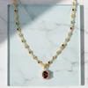 Gold necklace with gemstones on a marble surface