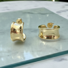 Gold hoop earrings on a glass surface with a marble background