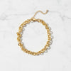 Gold chain anklet on a white textured background
