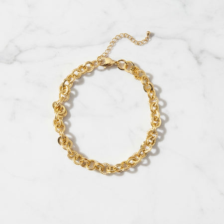 Gold chain anklet on a white textured background