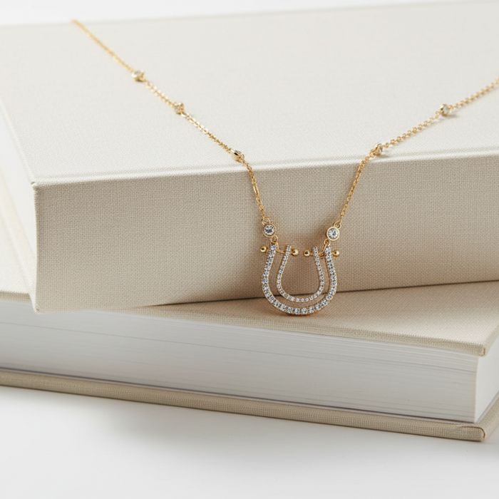 Gold necklace with a horseshoe pendant on a beige fabric surface