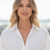 Woman wearing a white shirt and gold necklace with a blurred background