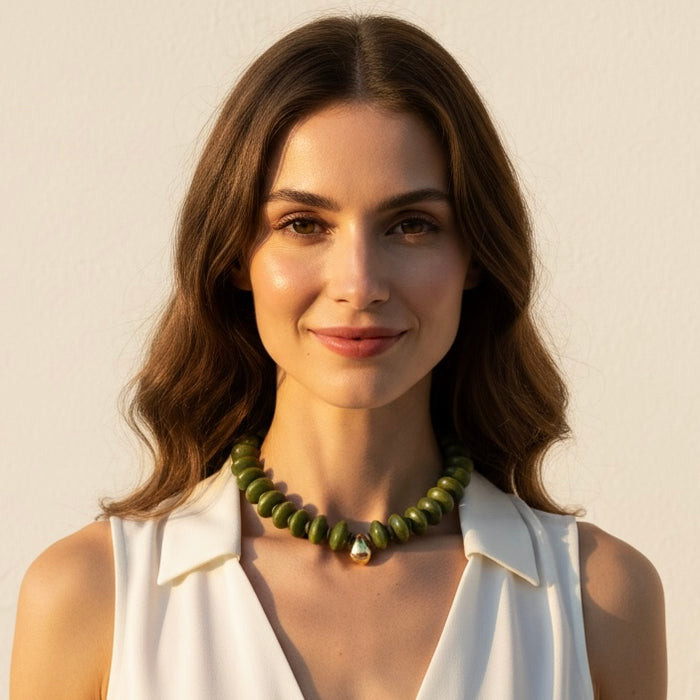 Woman wearing a green beaded necklace against a plain background
