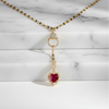 Necklace with a heart-shaped red gemstone pendant on a marble background