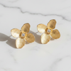 Gold flower-shaped earrings on a marble surface