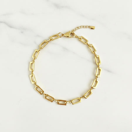 Gold chain anklet on a white marble surface