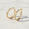 Gold hoop earrings with embedded stones on a light background