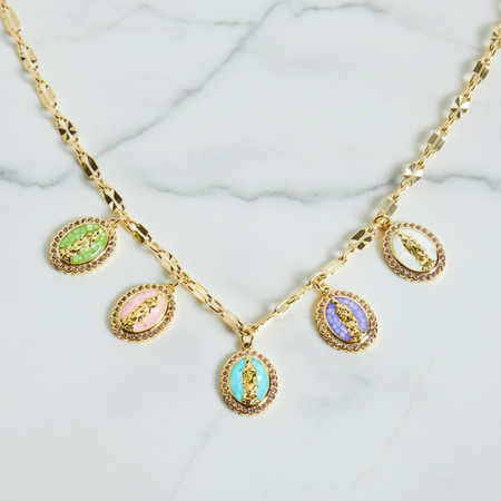 Gold necklace with colorful pendant charms on a marble surface