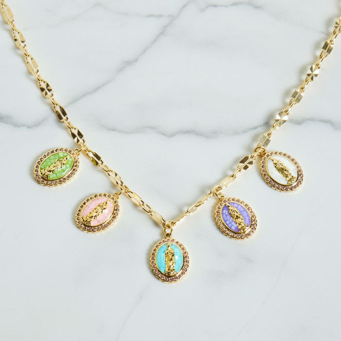 Gold necklace with colorful pendant charms on a marble surface