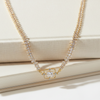Gold necklace with diamond pendant on a beige surface