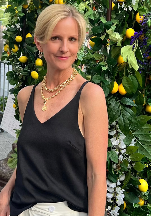 Woman in black top and white pants standing in front of a lemon tree