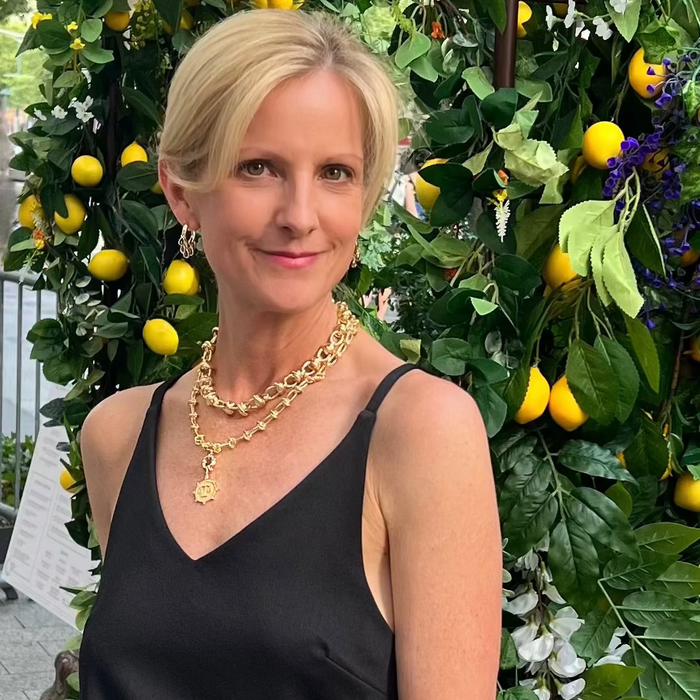 Woman in black top and white pants standing in front of a lemon tree
