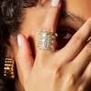 Close-up of a hand wearing a gold ring with a blurred background