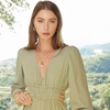 Woman wearing a green jumpsuit with a scenic background