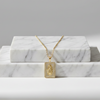 Gold necklace with a pendant on a marble surface