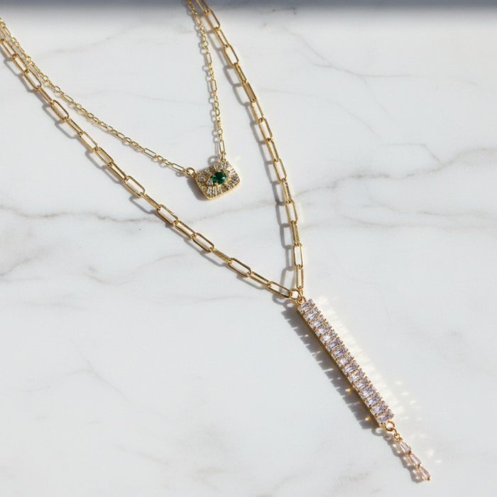 Two gold necklaces on a marble surface