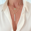 Gold necklaces with green gemstone and chain design on a white shirt background
