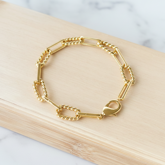 Gold bracelet on a wooden block with a marble background