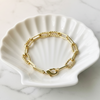 Gold bracelet on a white shell dish with a marble background