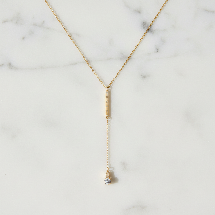 Gold necklace with a pendant on a marble background