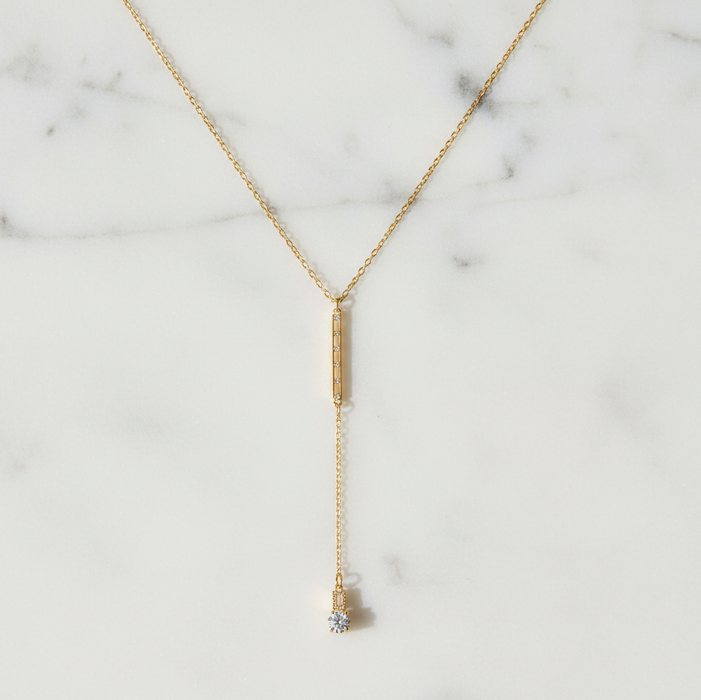 Gold necklace with a pendant on a marble background