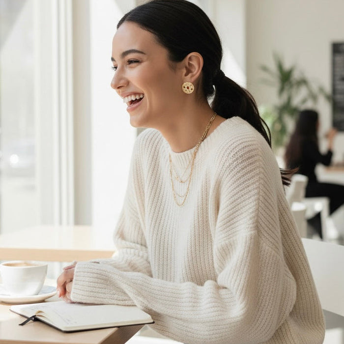 Woman in a white sweater sitting at a table in a bright room, smiling.