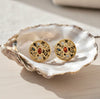 Gold earrings with gemstones on a white shell