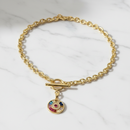 Gold chain necklace with a colorful charm on a white background