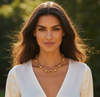 Woman wearing a gold necklace with a blurred green background