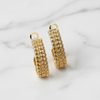 Gold hoop earrings on a light marble background