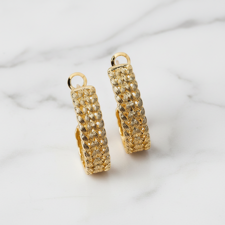 Gold hoop earrings on a light marble background
