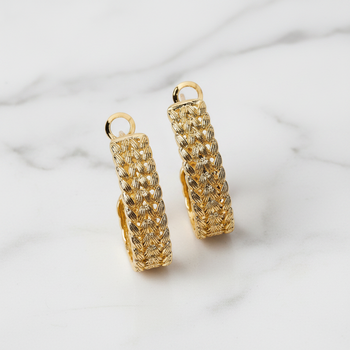 Gold hoop earrings on a light marble background