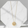 Gold necklace with a sunflower pendant on a marble surface