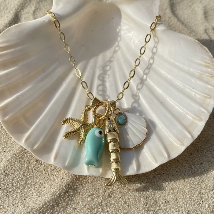 Necklace with charms on a large shell on sand