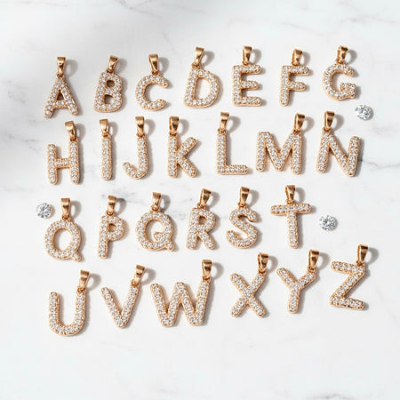 Gold alphabet letter pendants on a white background