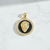Gold lion head pendant with black center and clear stones on a white marble background