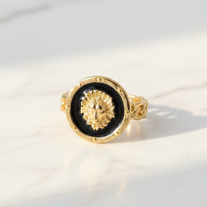 Gold ring with a black circular design on a light background