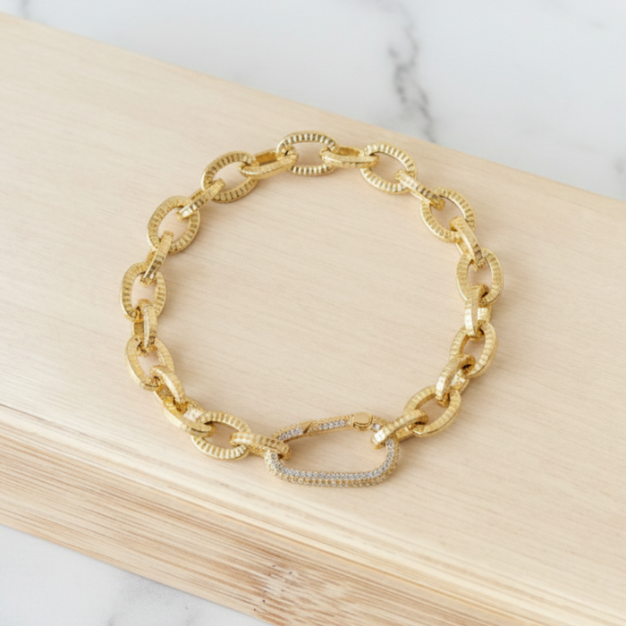 Gold chain bracelet on a wooden block with a marble background