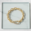 Gold chain bracelet on a clear glass surface with a marble background