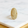Gold ring with textured surface on a marble surface