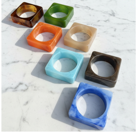 Set of colorful square-shaped bangles on a marble surface