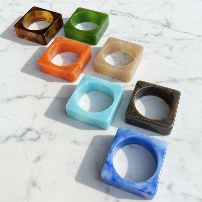 Set of colorful square-shaped bangles on a marble surface