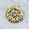 Gold sunburst decorative pin on a marble surface