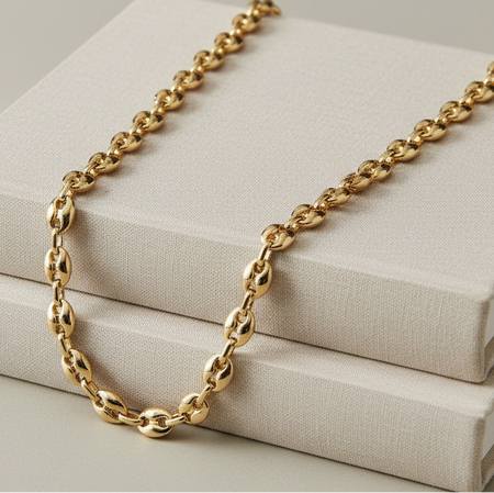 Gold chain necklace on a beige fabric surface