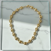 Gold chain necklace on a glass surface with a marble background